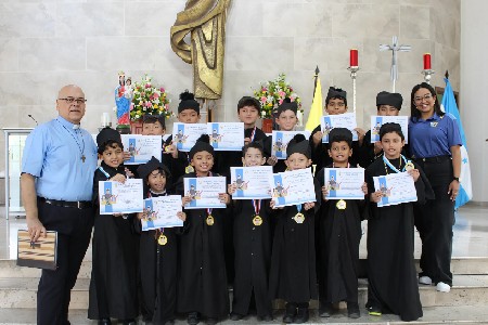 Estudiantes caracterizados como Don Bosco recibieron el reconocimiento “Don Bosco de cada sección”, junto al padre rector Rodolfo Guzmán, SDB, durante la celebración de los 210 años del nacimiento del santo fundador.