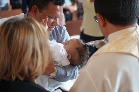 Uno de los niños bautizados recibe agua bendita en la cabeza, marcando su ingreso a la Iglesia Católica durante la primera ceremonia de bautismos comunitarios en la Parroquia El Espíritu Santo, Guatemala.