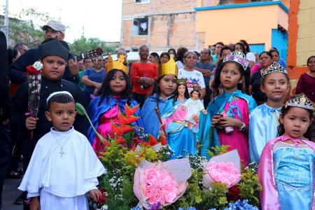 Niños de la comunidad parroquial se preparan con entusiasmo junto a la imagen de María Auxiliadora para dar inicio a la procesión, testimoniando su fe con alegría salesiana.