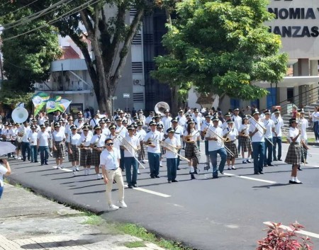 La Banda Padre Emeterio Serrano (BAMPES) del Instituto Técnico Don Bosco desfila con orgullo en el XXVI Encuentro de Bandas Musicales Estudiantiles en la ciudad de Panamá, destacándose por su precisión y elegancia.