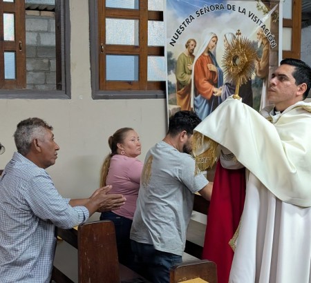 El padre eleva en adoración a Jesús Sacramentado, guiando a la comunidad en un momento de profunda reflexión y fe.