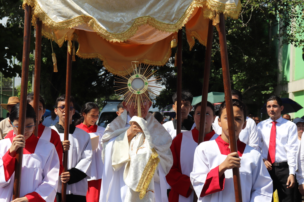 Feligresía junto al Cuerpo de Cristo en la procesión por las calles circundantes de la Parroquia María Auxiliadora, Don Rúa.
