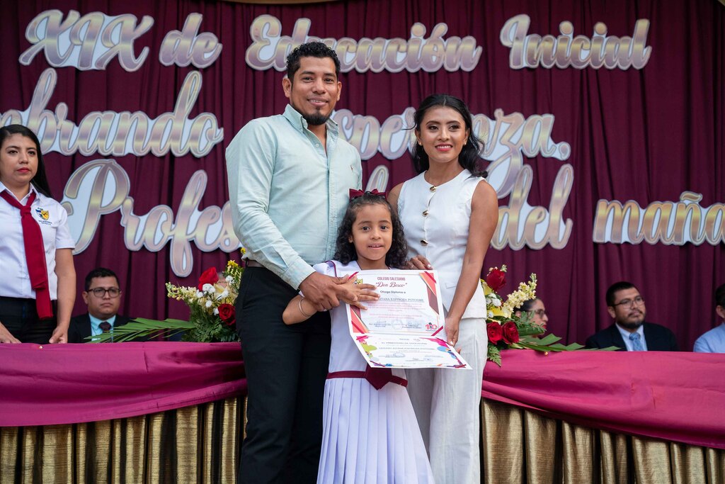 Estudiante festeja su promoción junto a sus padres, en un ambiente de alegría y orgullo.
