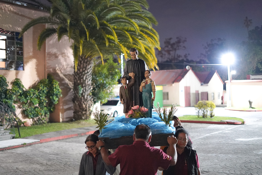 Feligreses de la Parroquia El Espíritu Santo participan con fervor, llevando la imagen de San Juan Bosco hacia el salón parroquial, como parte de la celebración en su honor.