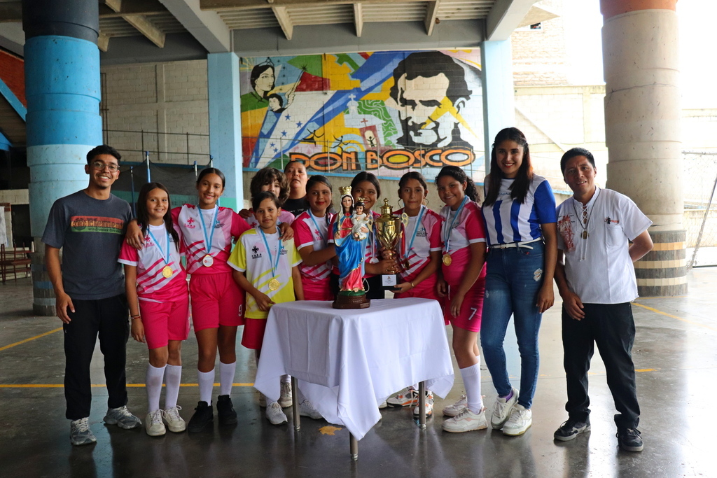 Con alegría y espíritu deportivo, las estudiantes campeonas posan junto a María Auxiliadora tras ganar el torneo femenino en la sede parroquial.