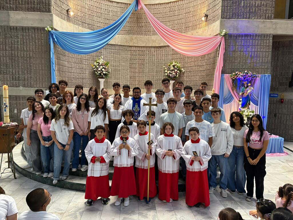 Estudiantes de undécimo año posan junto al padre Douglas Pérez, SDB, al finalizar la misa en honor a María Auxiliadora.