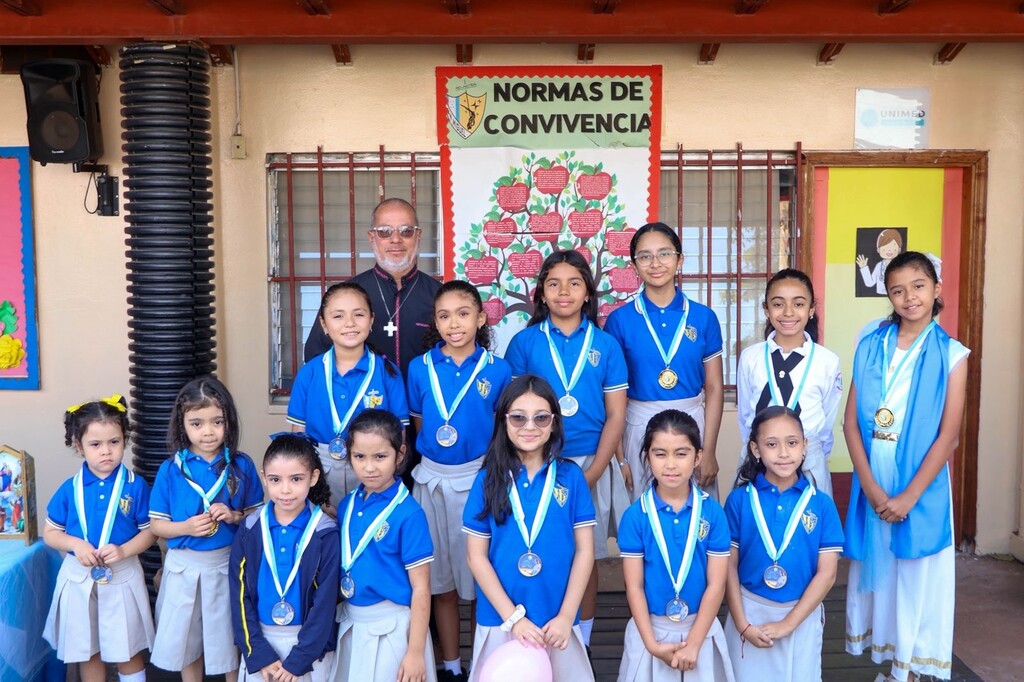Estudiantes de uno de los grados destacados reciben medallas durante la premiación del cierre del Mes Mariano.